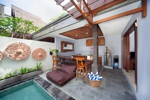 A modern outdoor kitchen area with a pool, seating, and a pergola. - Kusuma Living and Villa Seminyak (Denpasar)