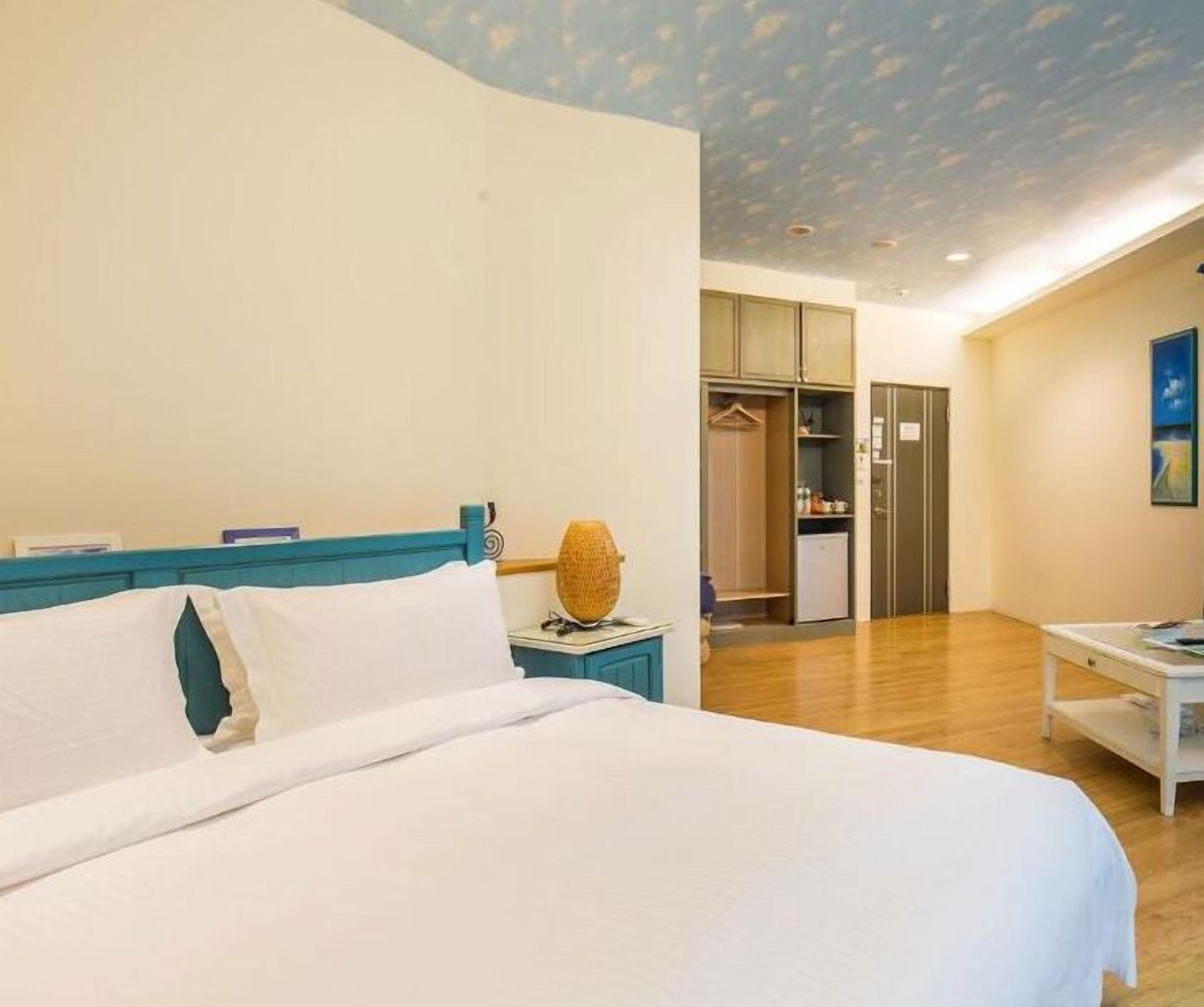 Une chambre comprenant un lit, une table de chevet, une armoire et un coin cuisine.