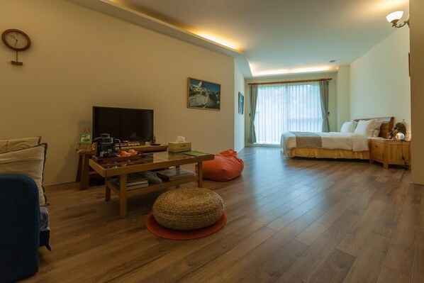 A cozy hotel room with a bed, a TV, a coffee table, and a window with curtains. - Tree Lake B&B (Shoufeng)