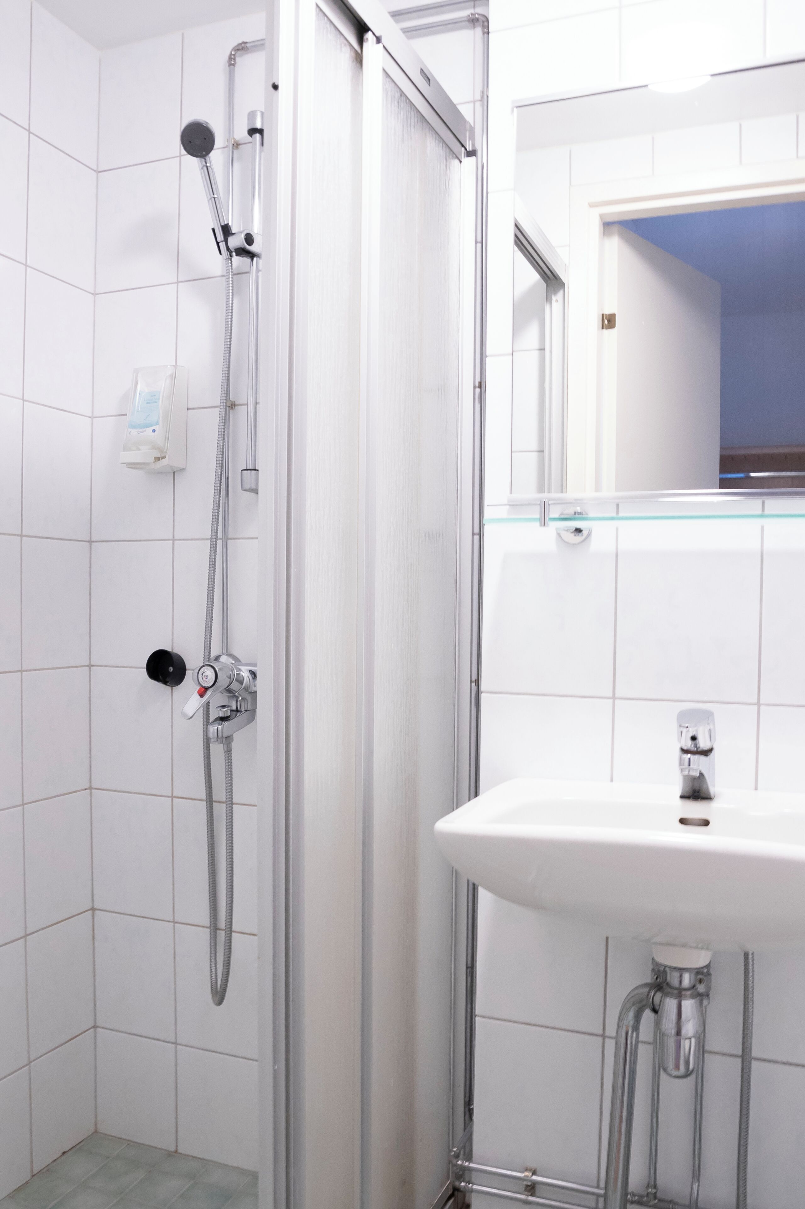 Un baño moderno con cabina de ducha de vidrio, un lavabo blanco y un espejo sobre él.