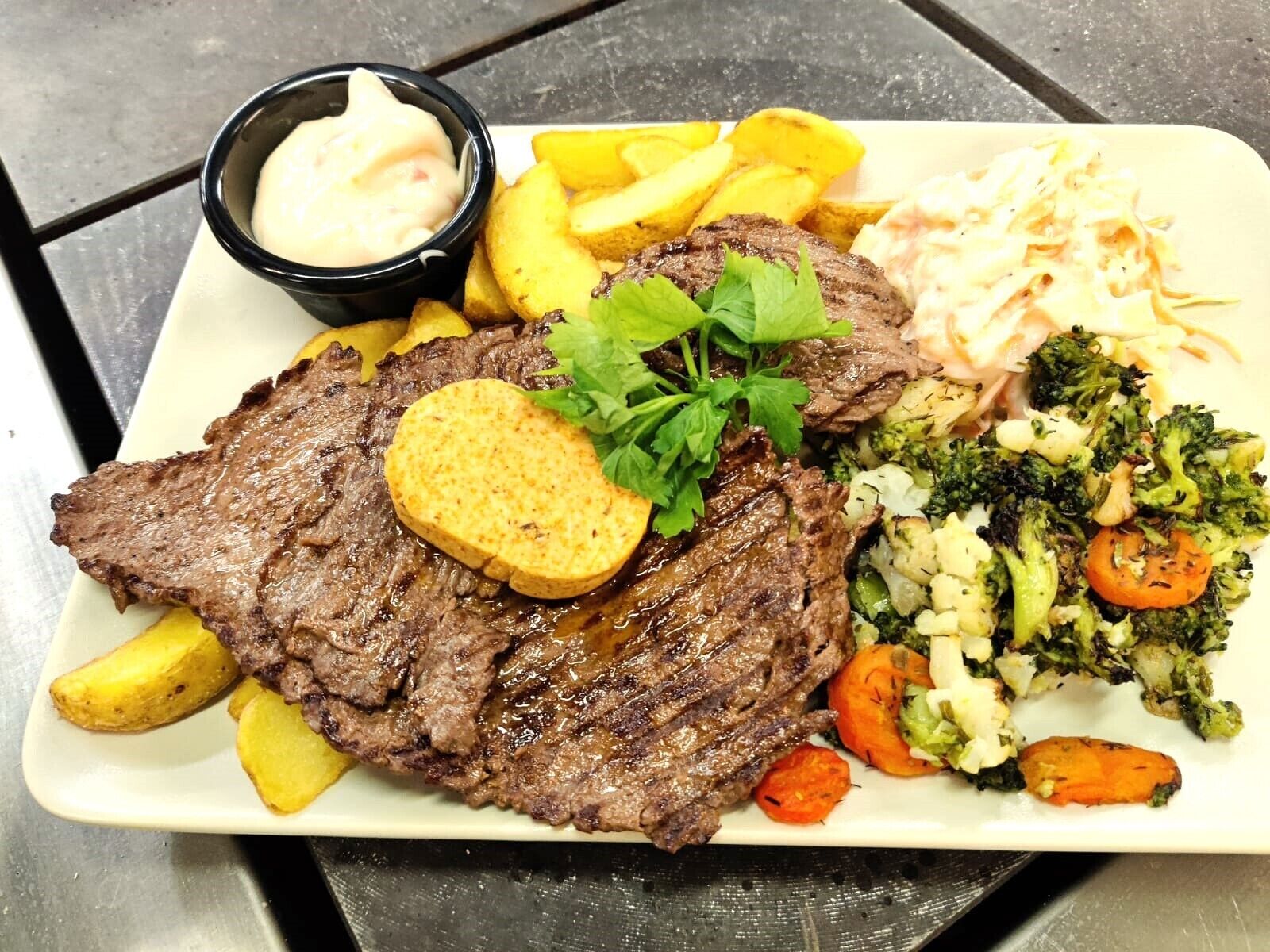 Ein Teller mit Fleisch, Bratkartoffeln und Gemüse.