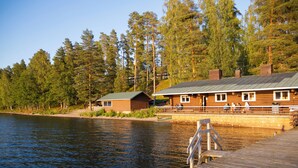 Una cabaña con un muelle que se adentra en un lago, rodeada de un bosque denso.