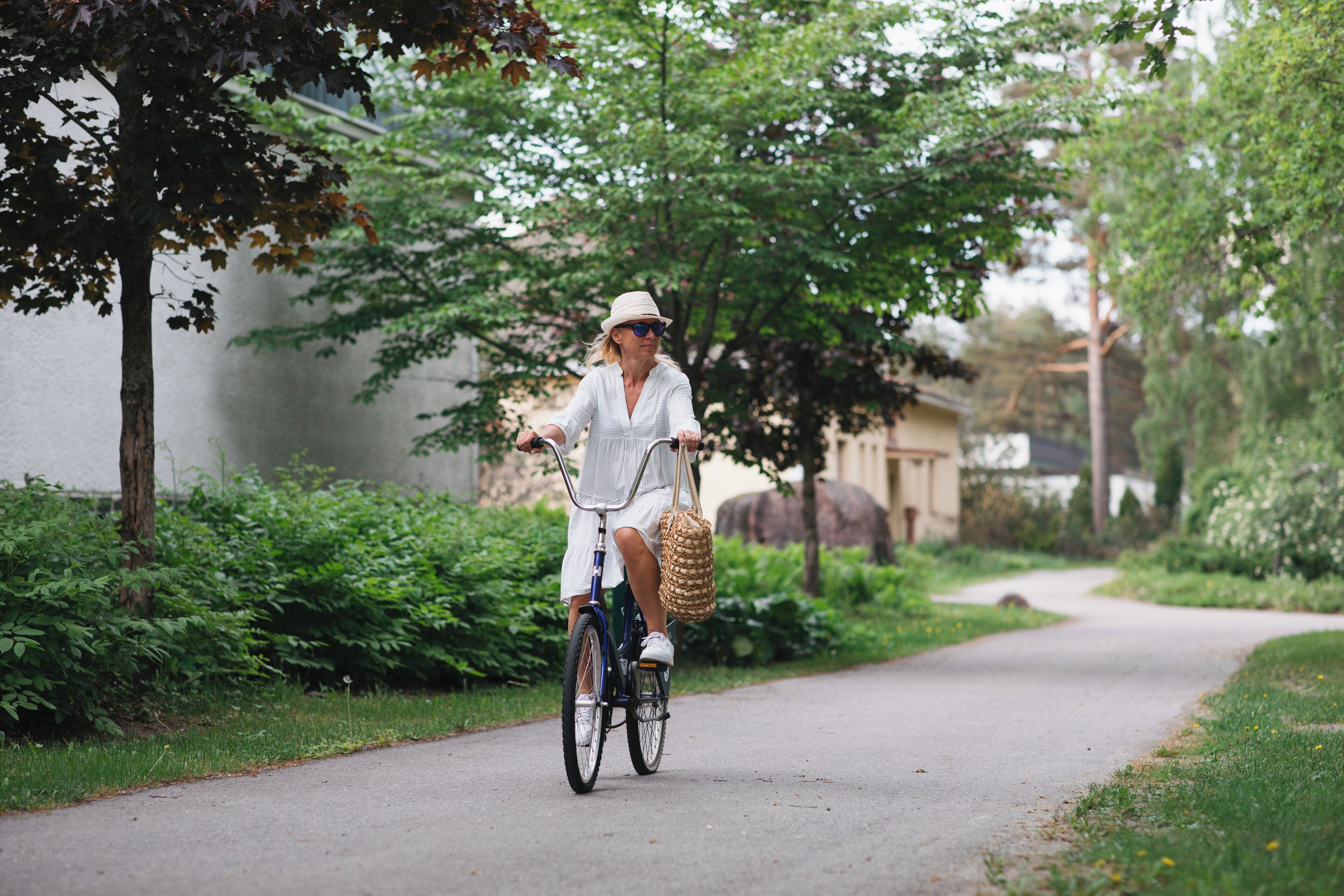 A person riding a bicycle on a paved path surrounded by greenery.