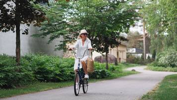A person riding a bicycle on a paved path surrounded by greenery.
