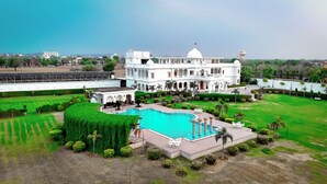 A large white building with a pool and manicured gardens.