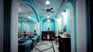 A room with a ceiling fan, a chandelier, and a reception desk.
