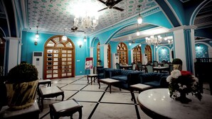A spacious lobby with a high ceiling, chandeliers, and a seating area with sofas and tables.