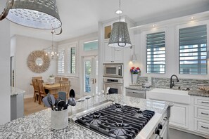 Prepare meals in the spacious kitchen with a gas stove and ample counter space, complemented by a dining area with a table and chairs.
