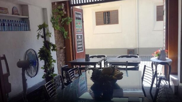 A dining area with tables and chairs, a fan, and a sign indicating fast food and lunch options. - Dutch Villa (Galle)