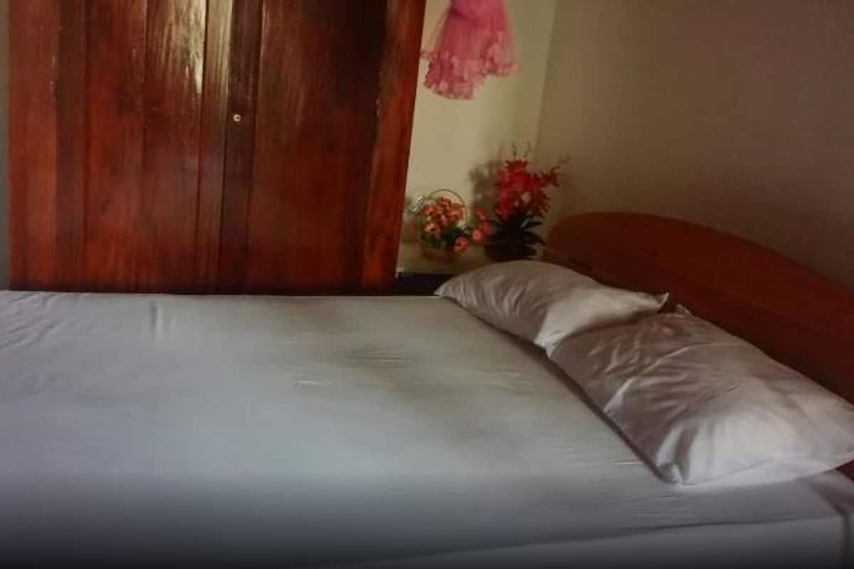 Una cama con ropa de cama blanca, un armario de madera y una pared con un diseño floral en rosa.