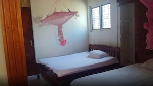 A bedroom with a single bed, a window with bars, and a door. - Dutch Villa (Galle)
