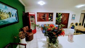 Un coin repas comprenant une table, des chaises, un vase avec des fleurs, un réfrigérateur et un tableau accroché au mur.