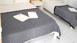 Une chambre d’hôtel avec deux lits, une petite table de chevet, un climatiseur fixé au mur et un tableau encadré accroché au mur.