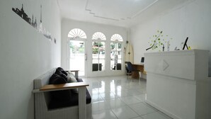 A spacious room with a white wicker sofa, a small wooden table, and a white cabinet with decorative items.