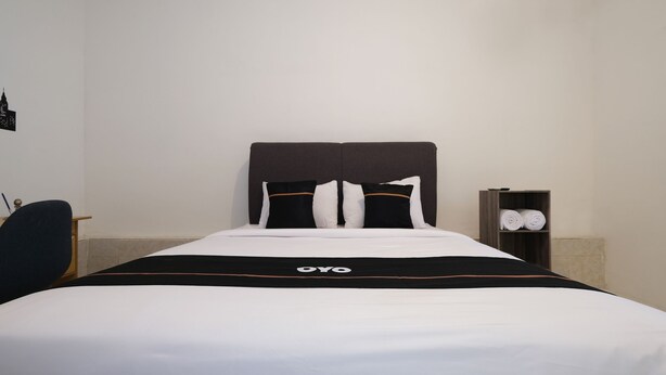 A neatly made bed with a black and white bedspread, a headboard, and two pillows.