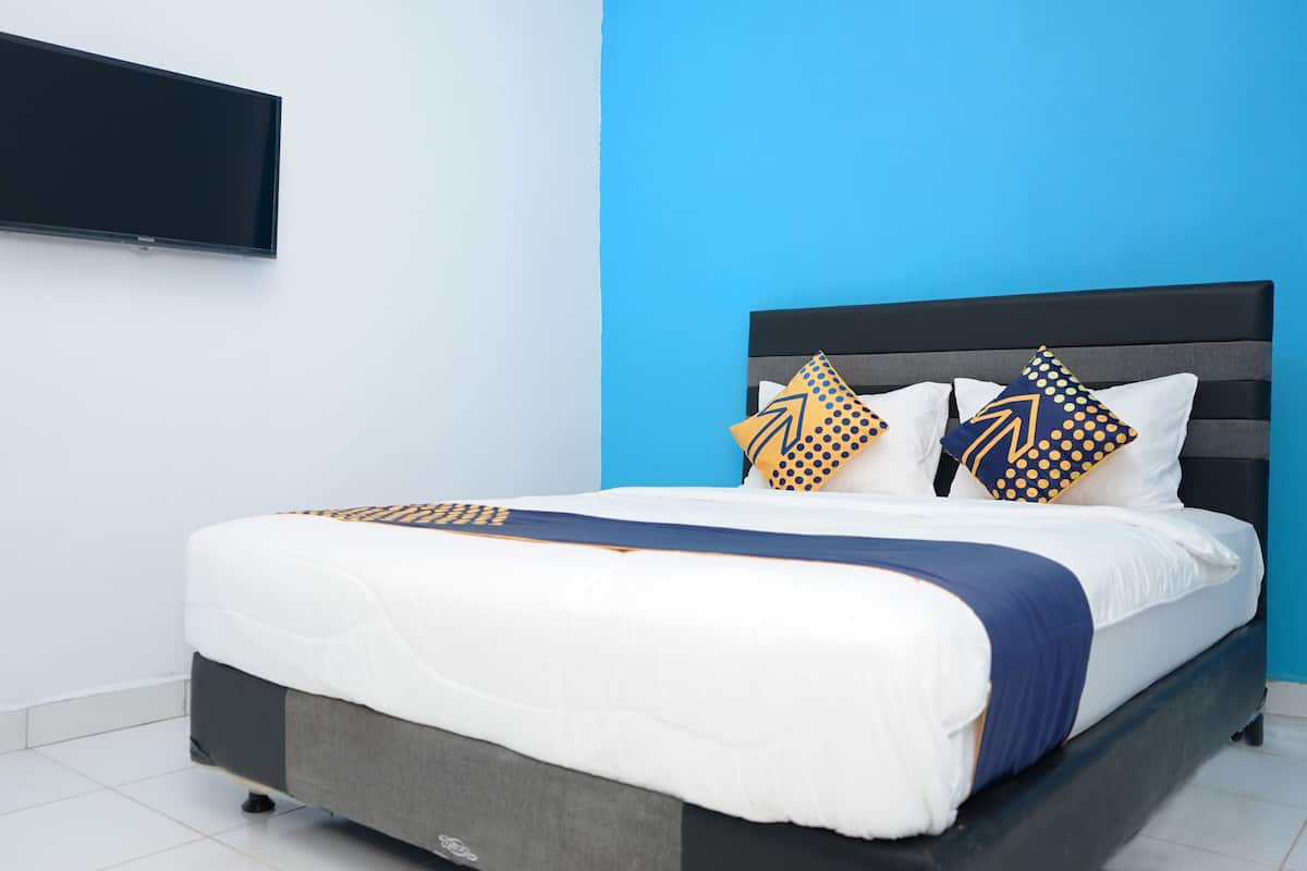 Ein modernes Schlafzimmer mit einem Bett, einem flachbildfernseher an der Wand und einer blauen Akzentwand.