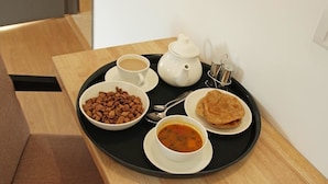 A tray with a cup of coffee, a teapot, a bowl of nuts, a plate of flatbread, and a bowl of soup on a wooden table. - Bh Boutique Hotel (Baruipur)