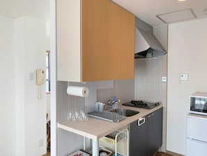 Una cucina compatta con un pensile in legno, forno a incasso, lavello con scolapiatti e un piccolo frigorifero.