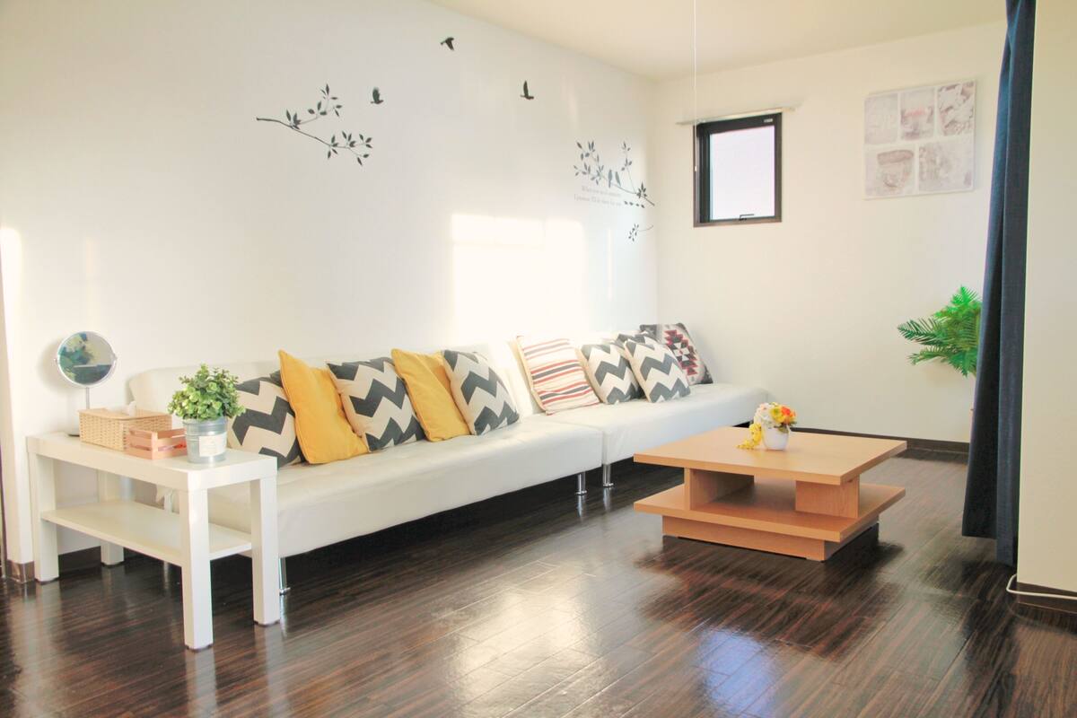 A modern living room with a white sofa, wooden coffee table, and a small side table with a plant.