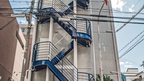 A tall building with a spiral staircase and a vending machine at the base. - Wabi Sabi Osaka (Osaka)