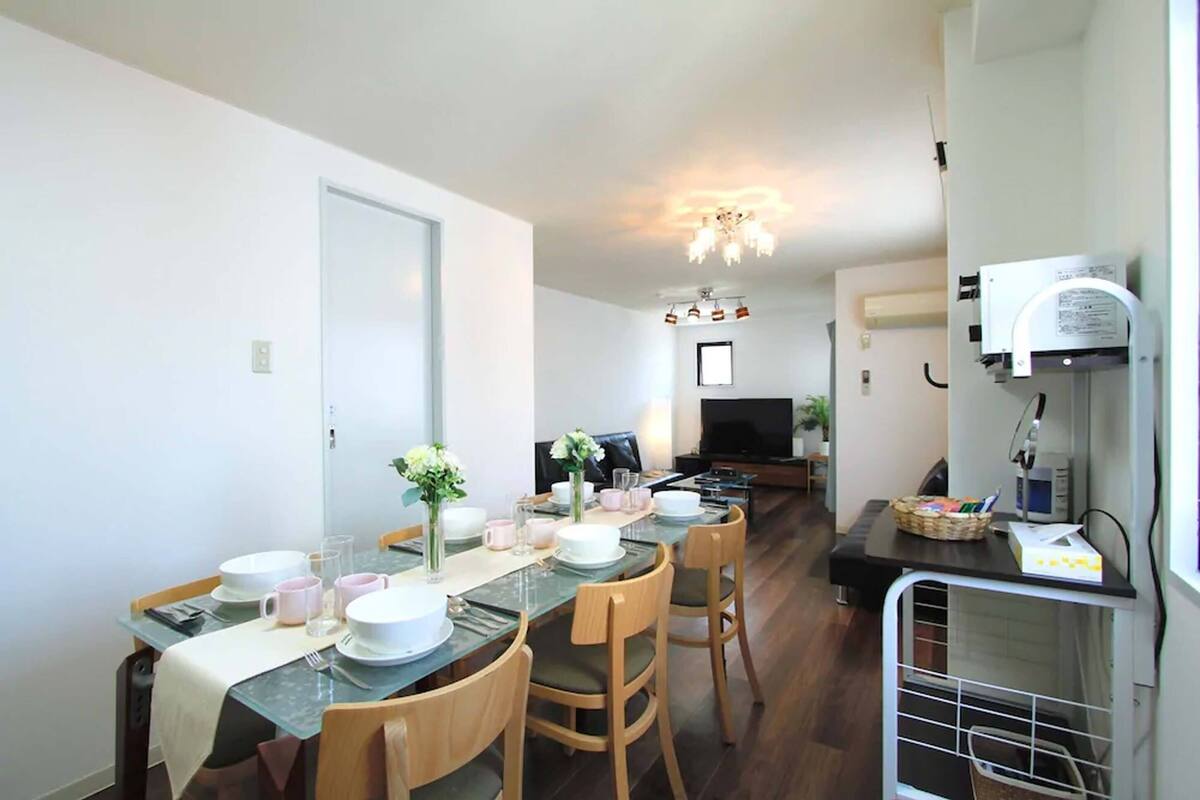 A dining area with a glass table, chairs, and a TV in the background.