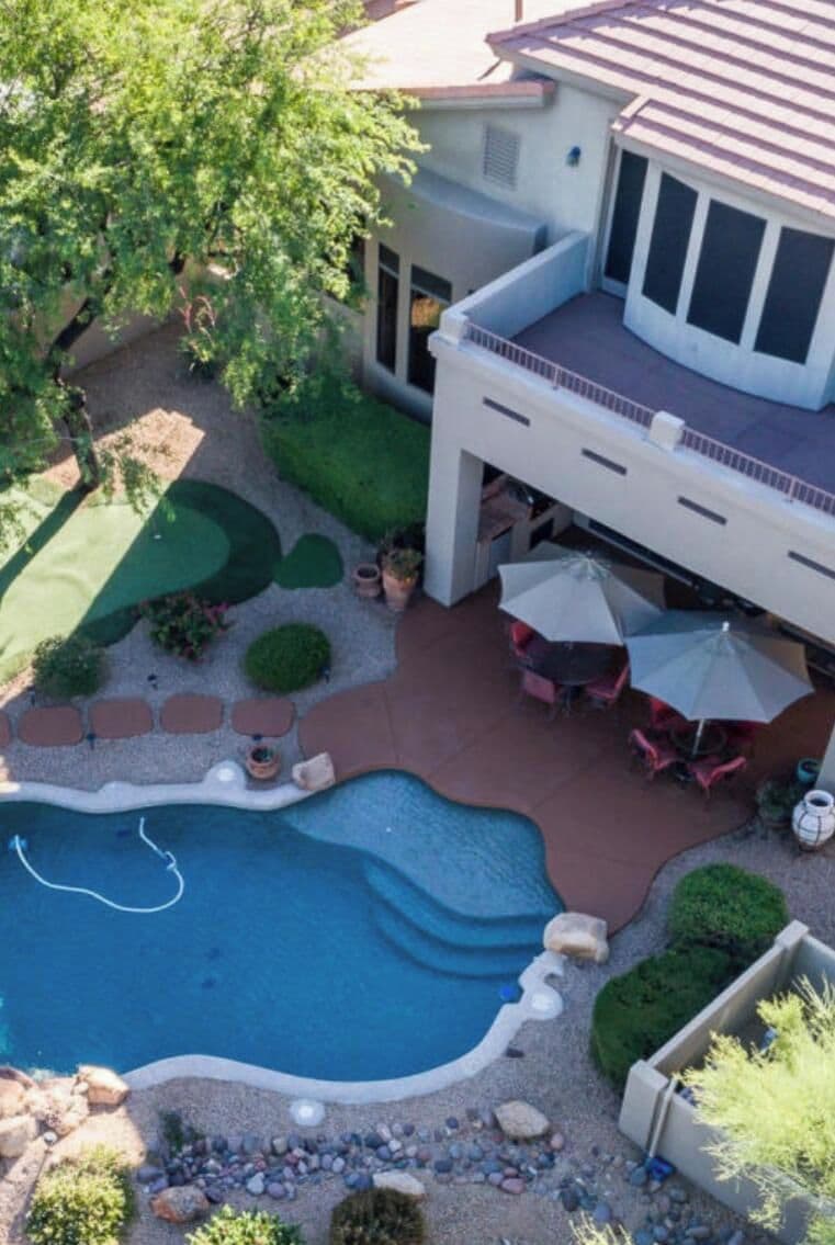 A residential property with a swimming pool, patio furniture, and a covered outdoor seating area.