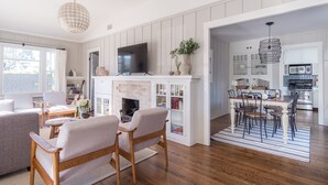 A modern living room with a fireplace, a dining area, and a kitchen.