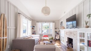 A cozy living room with a sofa, armchair, and a TV on a mantelpiece.