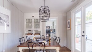 A dining area with a wooden table, black chairs, and a unique pendant light.