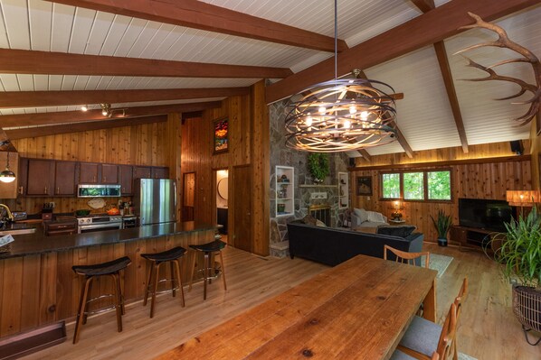 Une cuisine spacieuse avec des meubles de rangement en bois, un grand îlot central doté de tabourets et un luminaire suspendu.