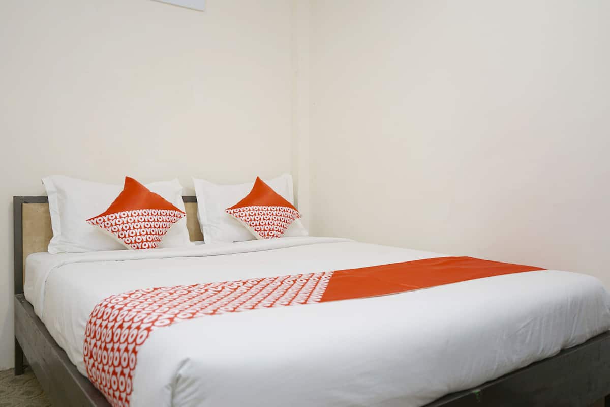 A neatly made bed with white and orange bedding, including patterned pillows and a blanket.