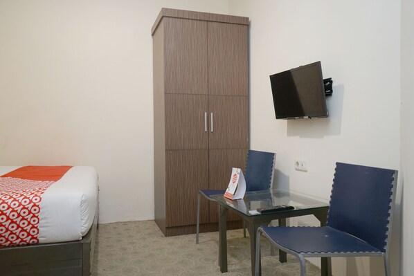 A hotel room with a bed, a wardrobe, a desk with a chair, and a flat-screen TV mounted on the wall. - OYO 2536 Hotel Tanjung (Makassar)