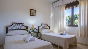 Une chambre d’hôtel avec deux lits, une table de chevet avec une lampe et une fenêtre avec des rideaux.