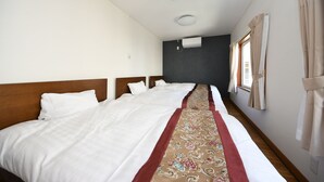 Habitación de hotel con dos camas, una pared oscura, una ventana con cortinas y una lámpara en el techo.