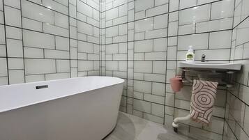 A modern bathroom with a freestanding bathtub, a sink, and a towel rack.