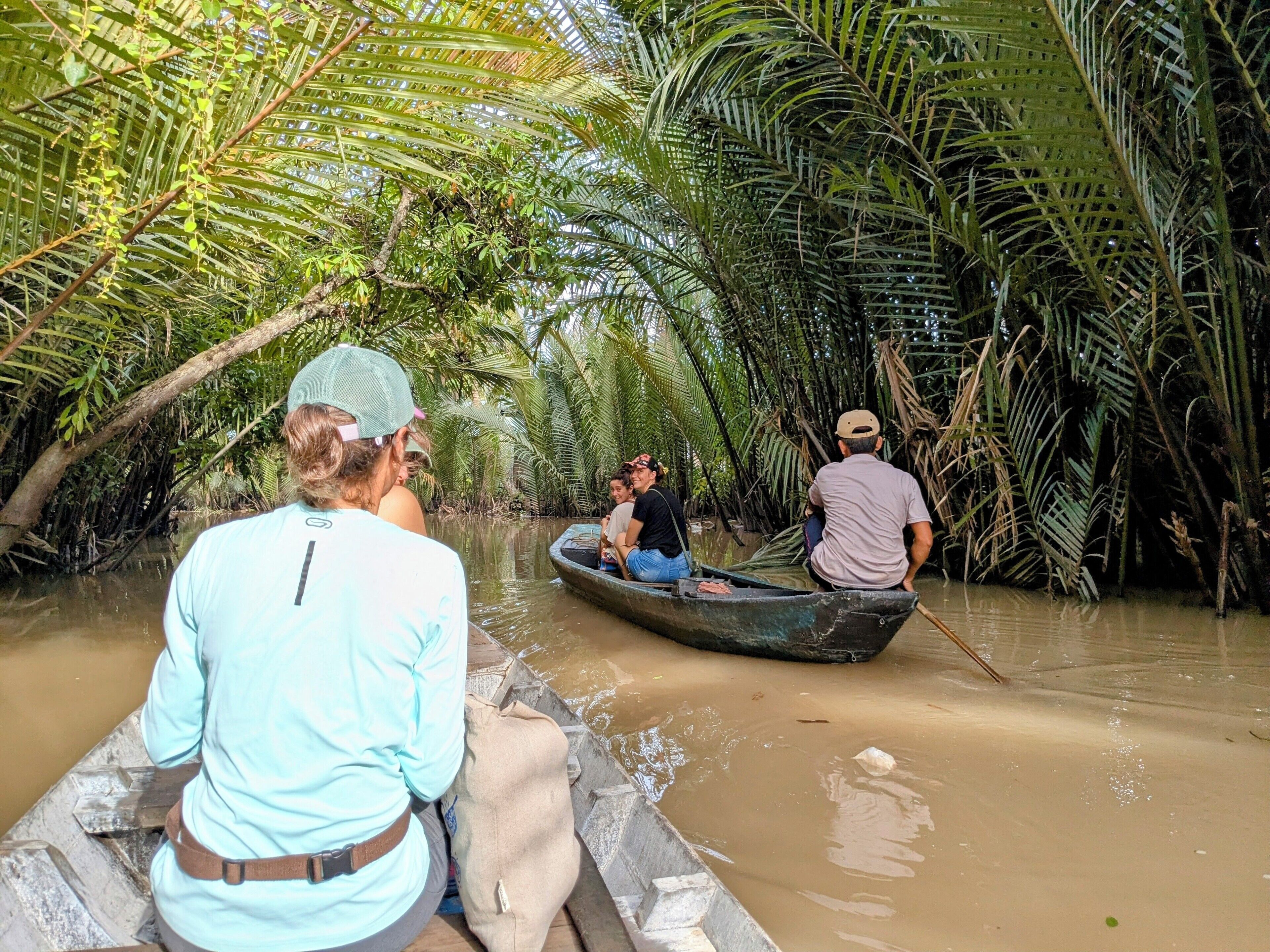 Eine Gruppe von Menschen fährt in einem Boot durch einen Mangrovenwald.