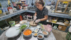 Une cuisine contenant divers aliments et ustensiles, notamment des bols remplis de légumes et d’épices, une planche à découper et un évier.