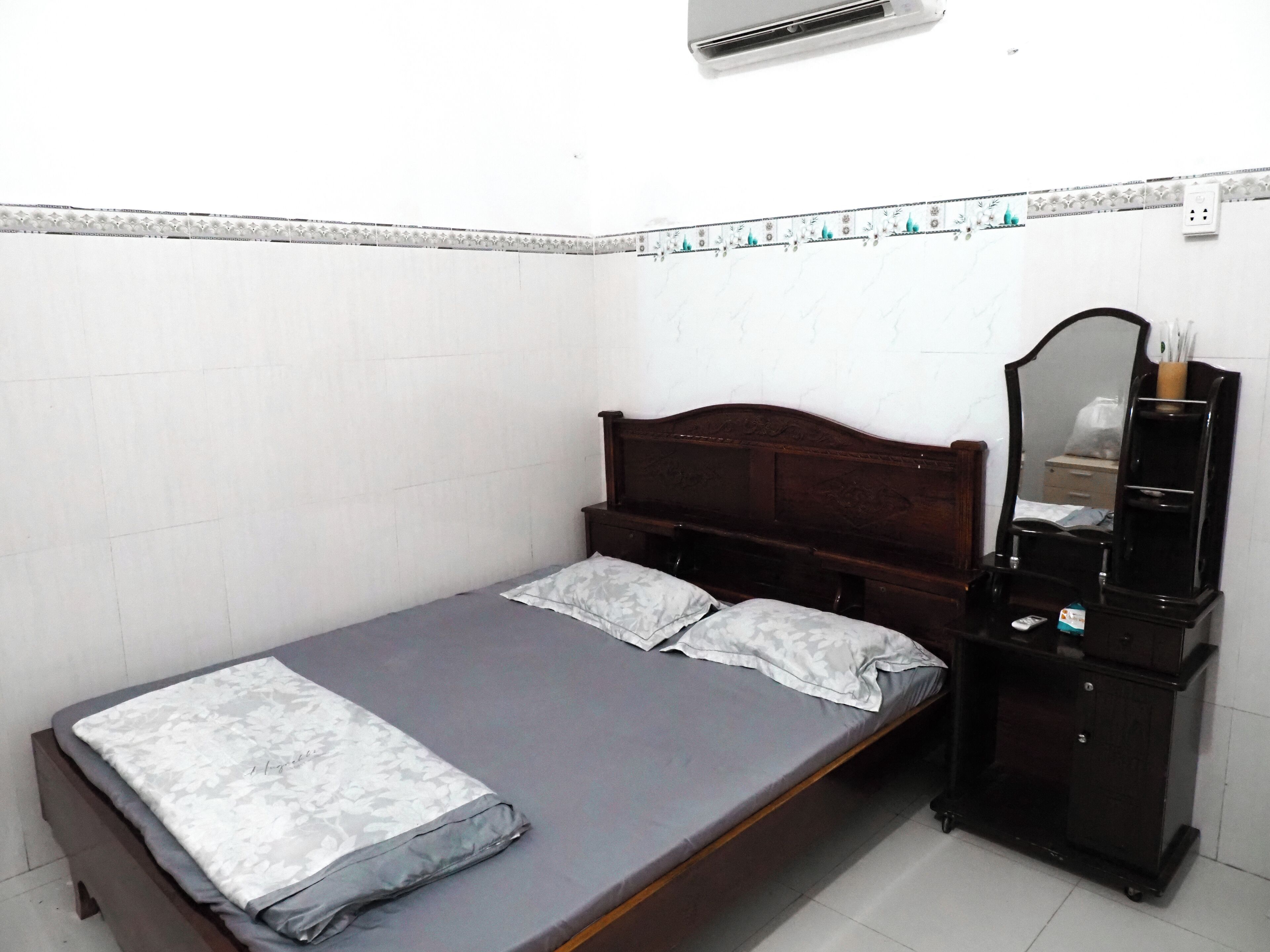 Un dormitorio pequeño y ordenado con una cama individual, un aparador y un espejo.