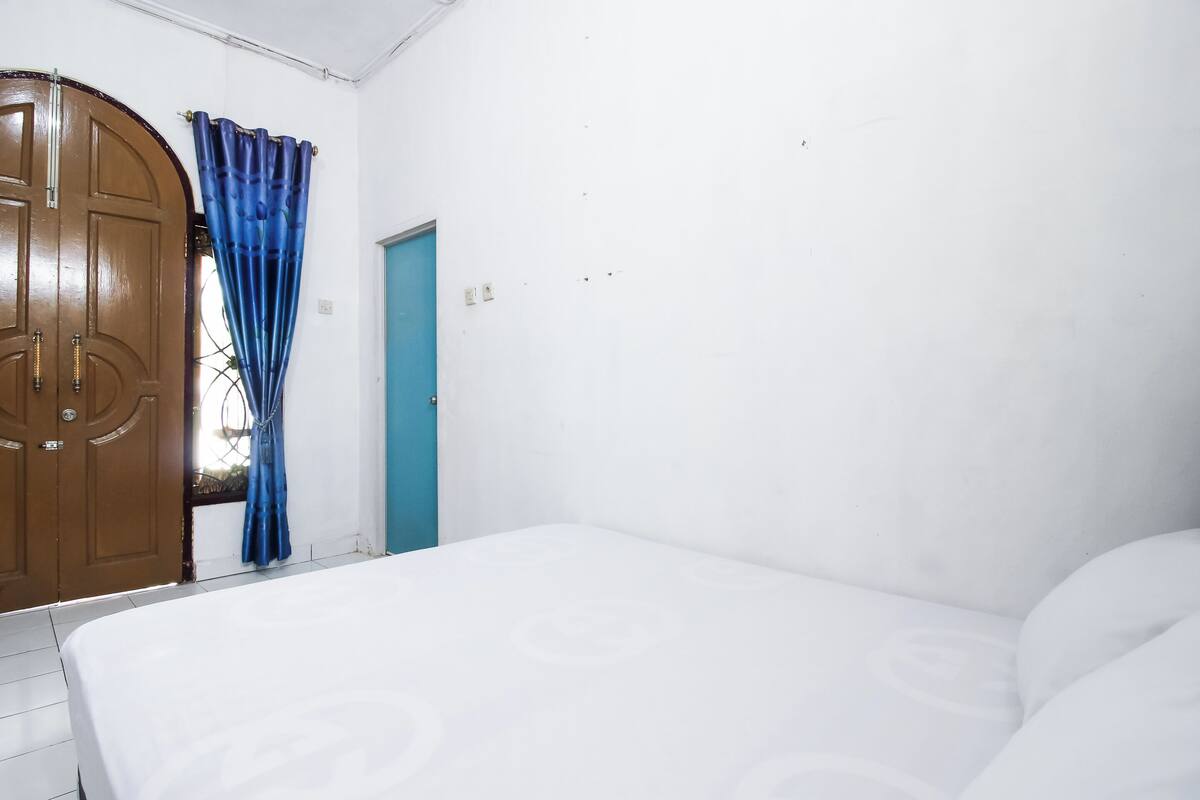 A room with a bed, a wooden wardrobe, a blue door, and a curtain.