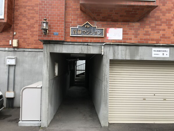 A narrow alleyway leading to a building with a garage door and a sign above it.