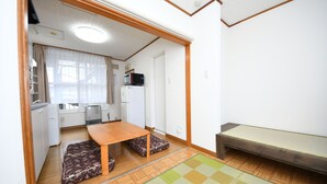 A compact living space with a kitchen area, a dining table, and a small seating area with cushions.