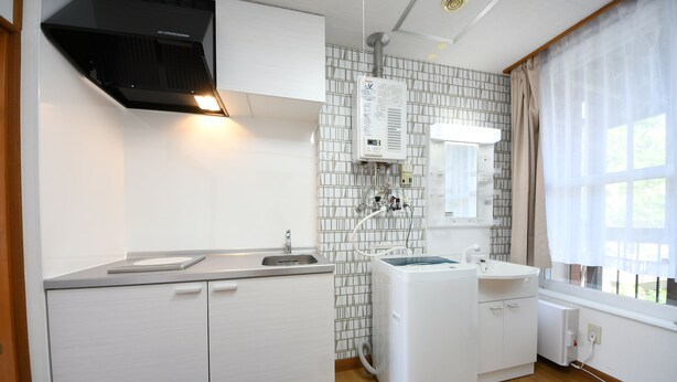 A compact kitchen with a sink, stove, and a built-in washing machine.