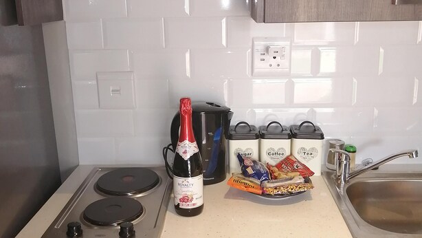 Une cuisine équipée d’une cuisinière à gaz, d’une bouteille de vin rouge et de récipients contenant du café et du thé.