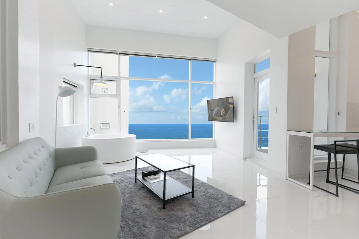 A modern living room with a large window, a sofa, a coffee table, and a TV.