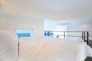 Una camera da letto moderna con un letto grande, un balcone con ringhiera e vista sul mare.