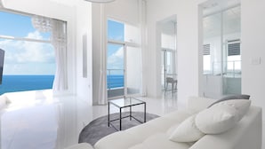 Una sala de estar moderna con un sofá blanco, una mesa de centro de vidrio y vistas al océano.