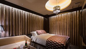 A hotel room with a large bed, a sofa, a glass coffee table, and a chandelier. - Hotel Glanz Cascata (Tokyo)