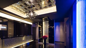 A modern lobby with a reception desk, a chandelier, and a glass wall with a blue light. - Hotel Glanz Cascata (Tokyo)