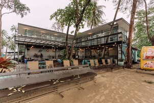 Un edificio moderno con fachada de vidrio, zona de estar al aire libre y palmeras.
