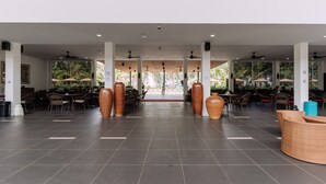 A spacious indoor area with multiple tables and chairs, large vases, and ceiling fans. - Roxy Sematan Villa & Townhouse (Lundu)